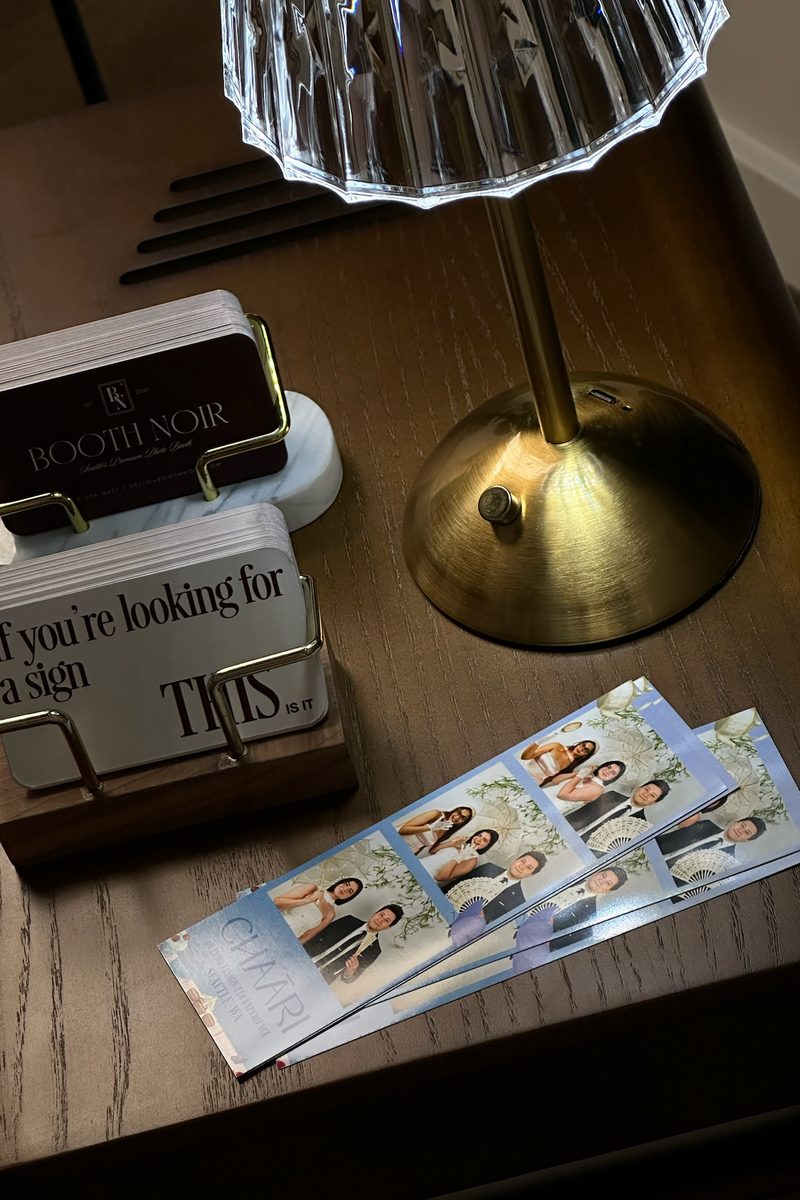Printed strips from the brand event on the booth's side table beside the Booth Noir cards
