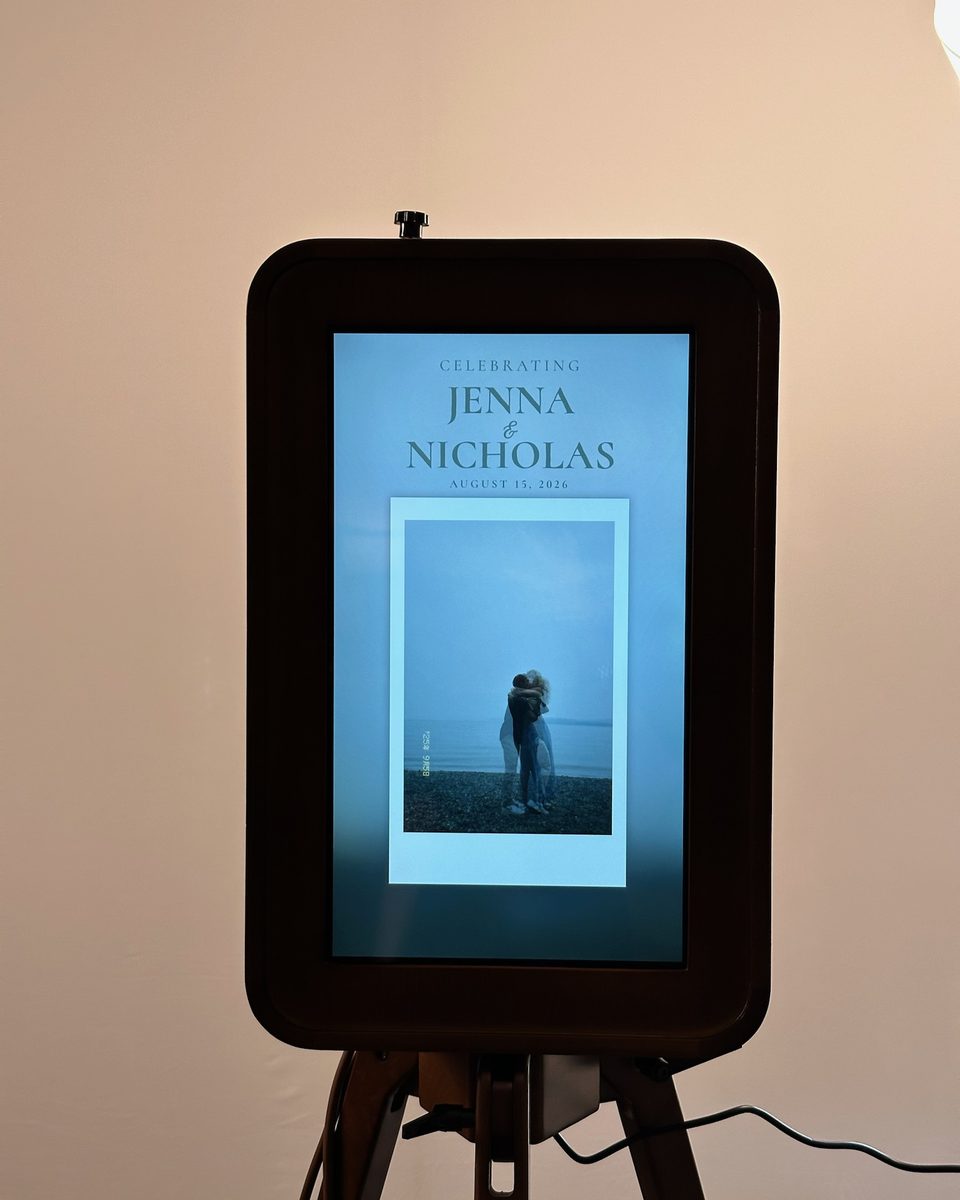 The booth in a dim room at night, its screen lit with the couple's names