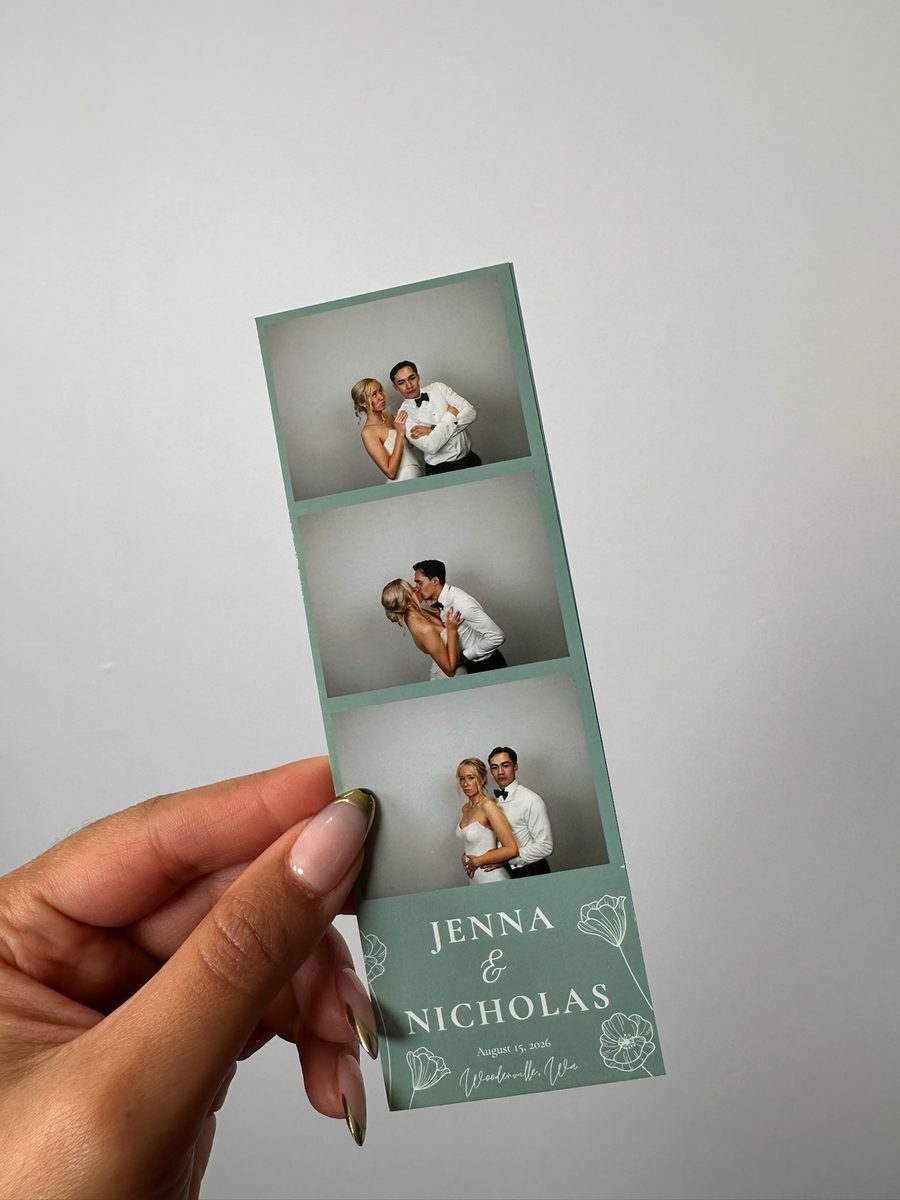 A hand holding a printed strip of the couple, with their names at the foot of the strip
