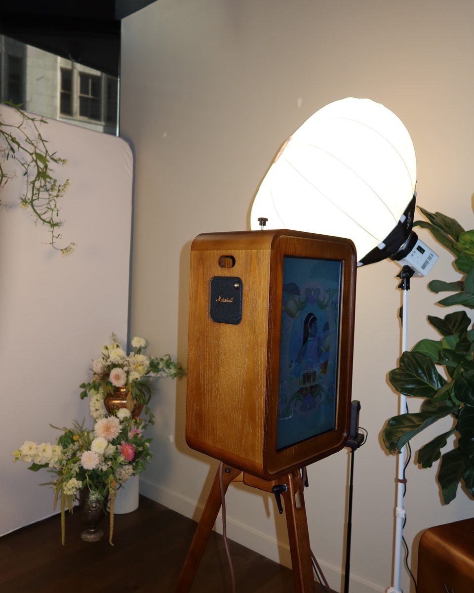The booth and a softbox beside a white backdrop and an arrangement of flowers