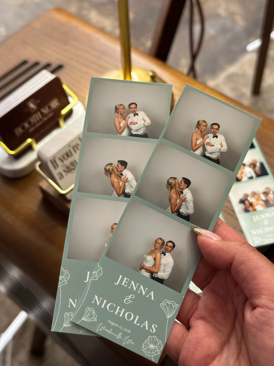 Two printed strips of the couple held up in front of the booth's side table