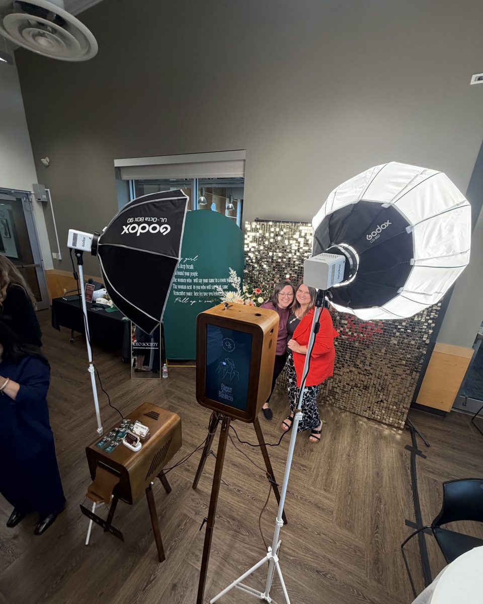 Two guests posing at the booth between the softbox lights at a conference