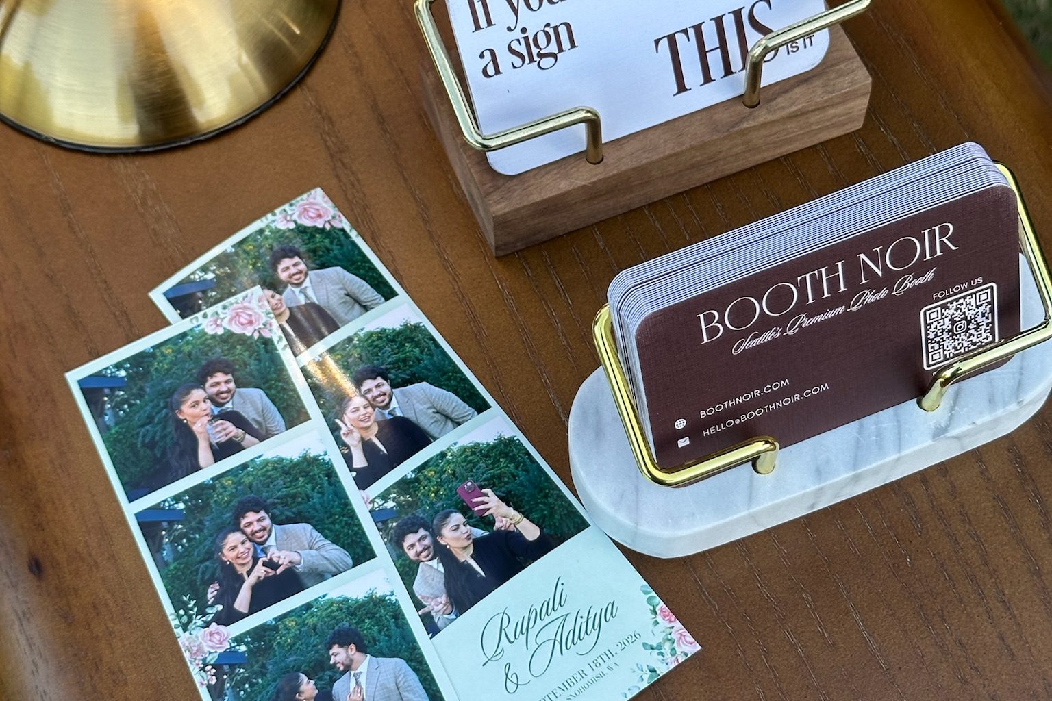 Printed strips from a wedding laid on the booth's side table beside the Booth Noir cards