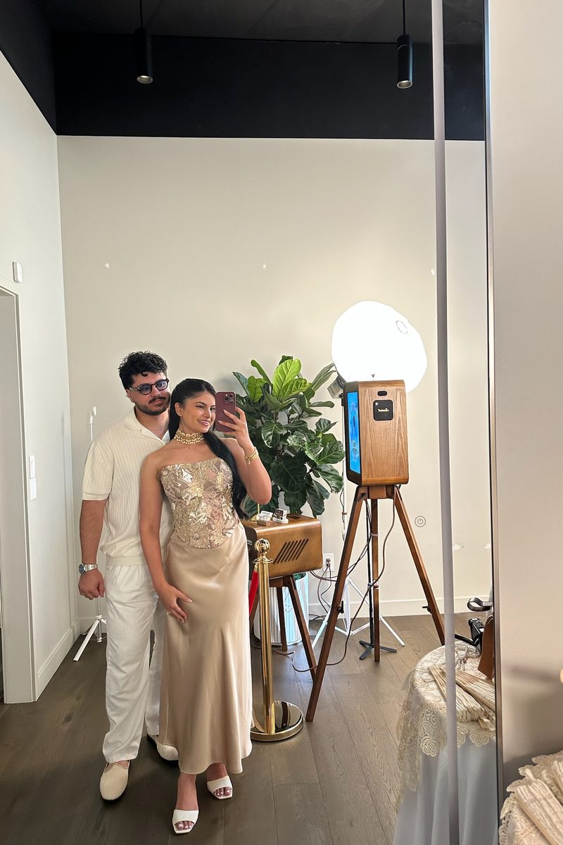 Adam and Raj beside the booth at a brand event, photographed in a mirror