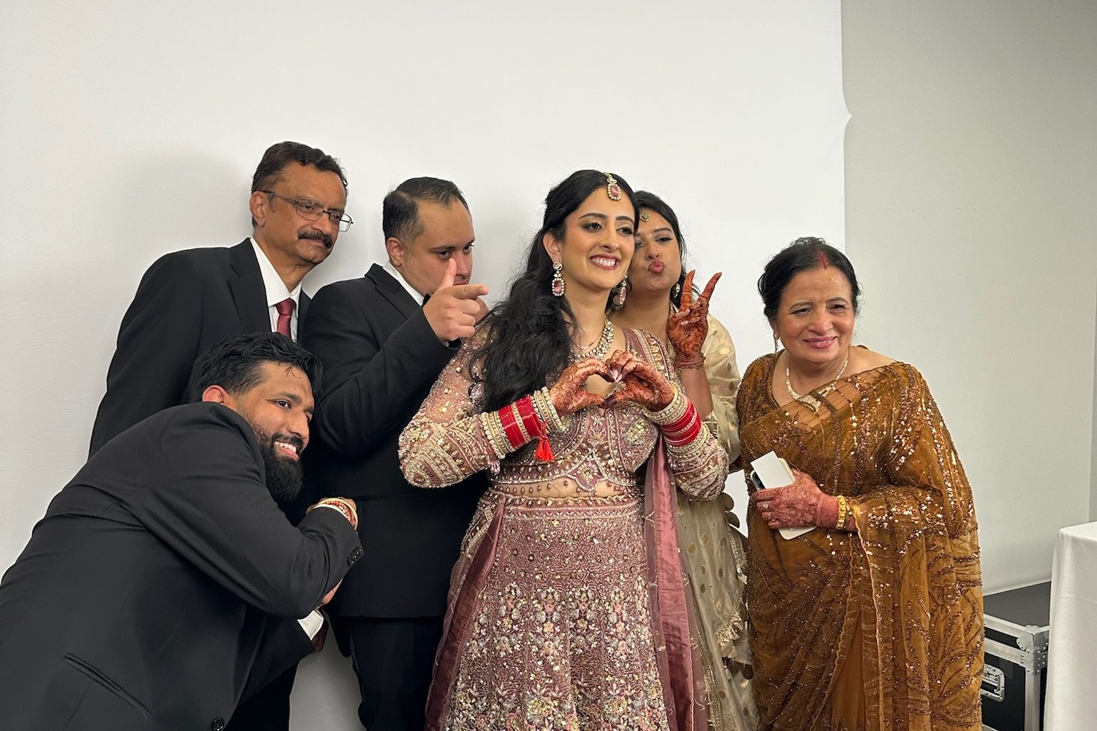 The bride and her family posing in front of the white backdrop, mid-pose